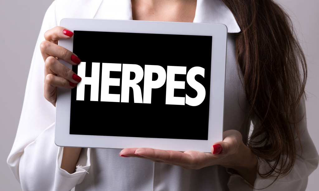 woman in doctors coat holding up board that says herpes