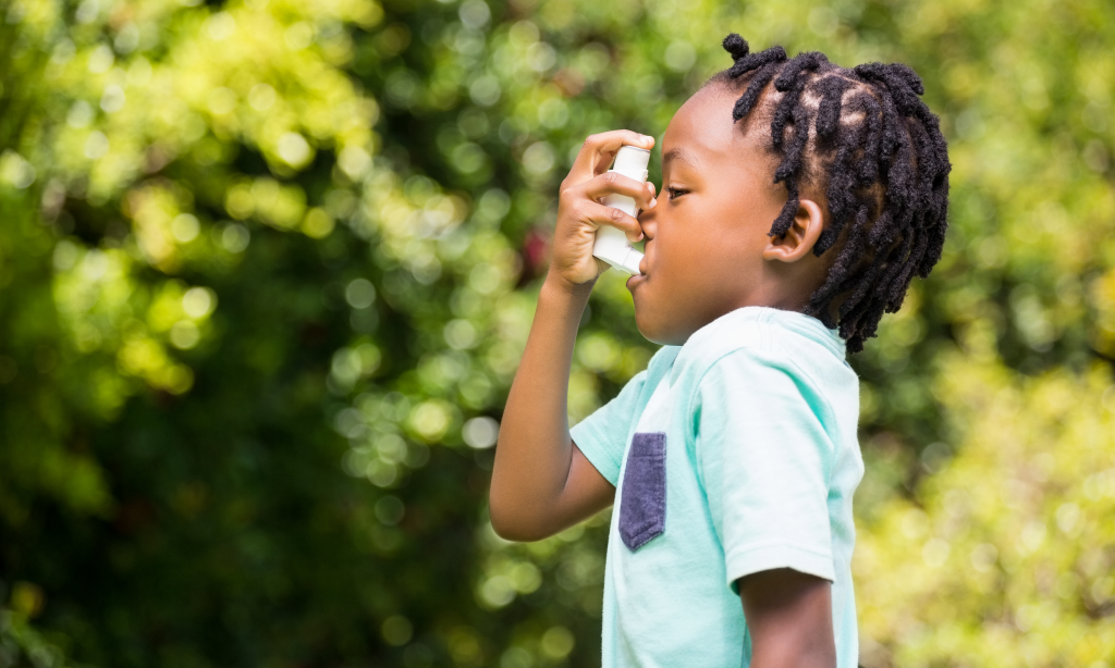 boy using asthma inhaler in the park