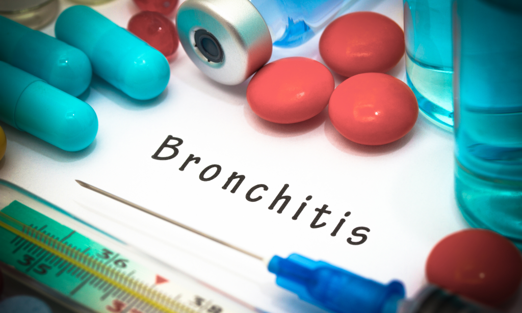 Bronchitis - diagnosis written on a white piece of paper. Syringe and vaccine with drugs