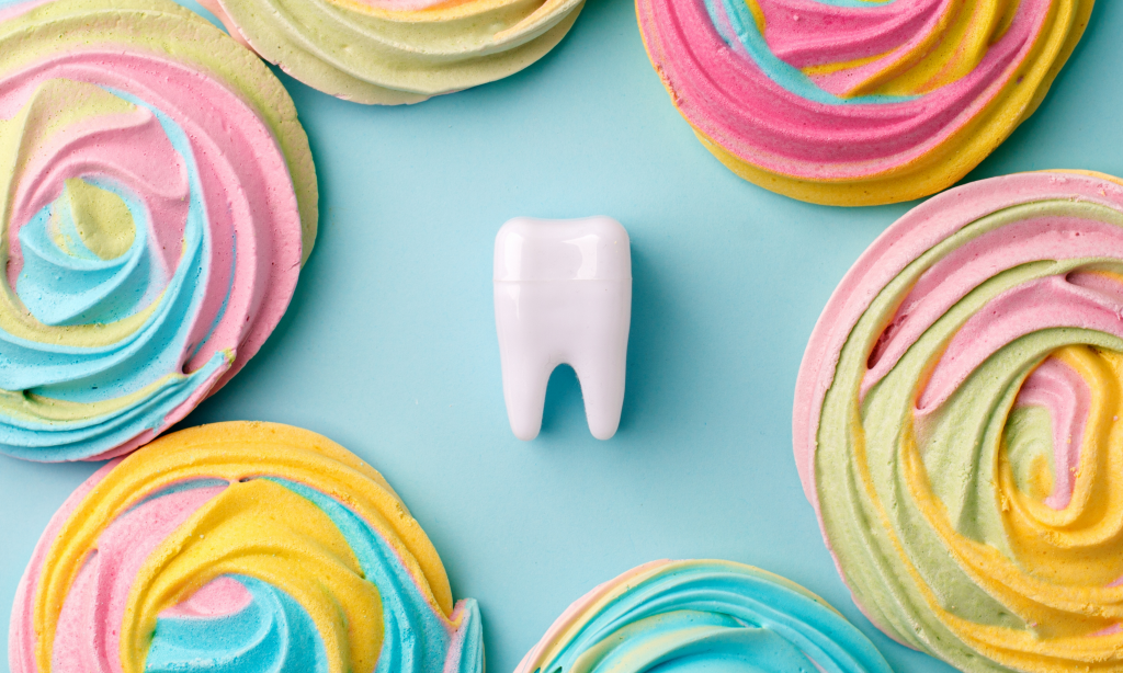 Plastic tooth in many colorfull rainbow sweetness from sugar. Caries and sugar concept. Dental care concept on blue background