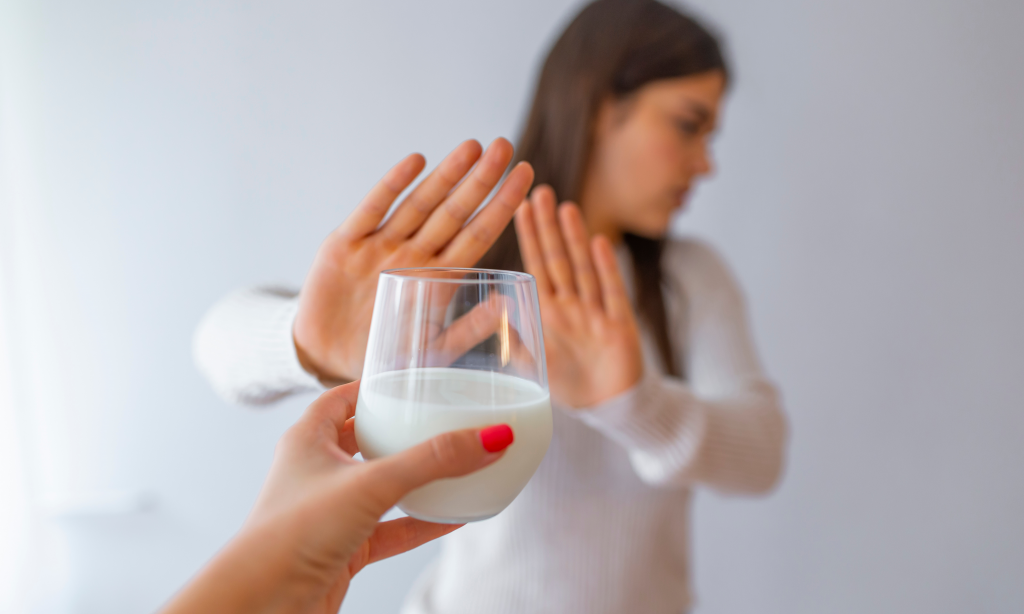 Lactose intolerance, health problem with dairy food products concept. Woman holding glass of milk having bad stomach ache. Young woman refusing to drink milk