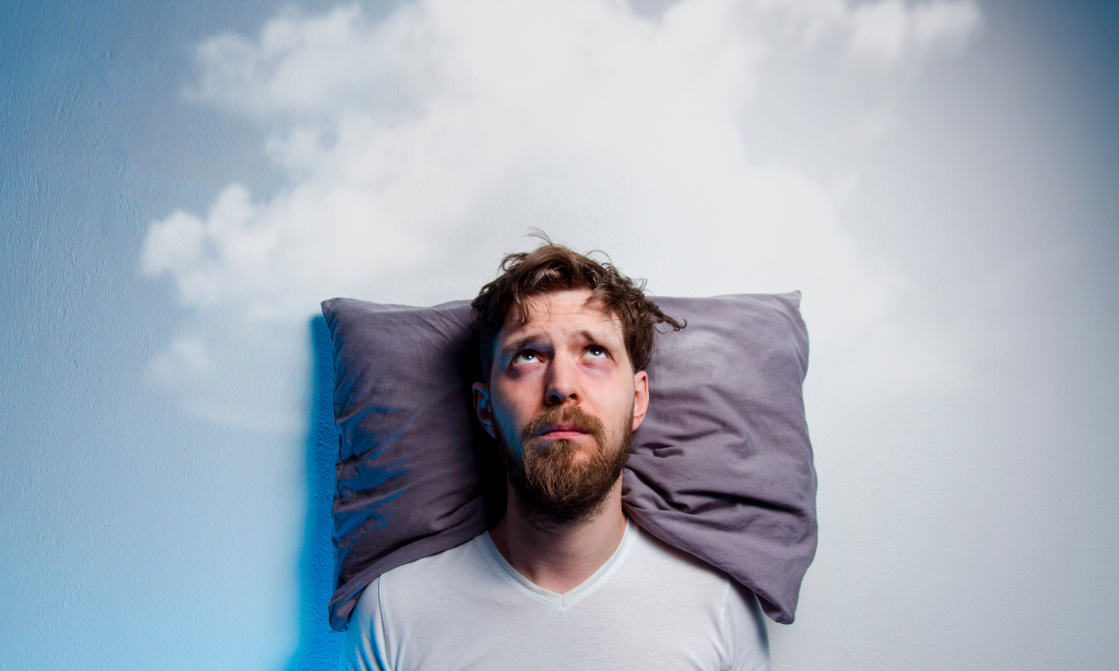 man having problems/insomnia, laying in bed on pillow, looking up to grey cloud over his head.