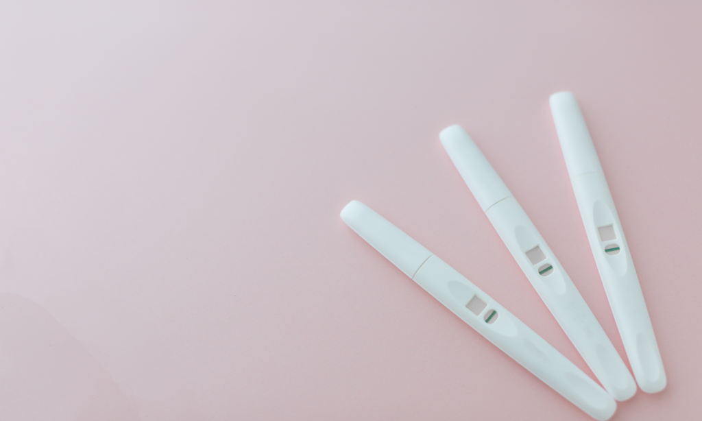 three white negative pregnancy tests on a pink background
